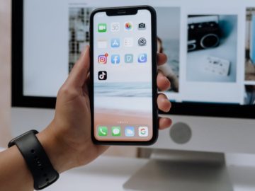 holding a smartphone in front of an imac